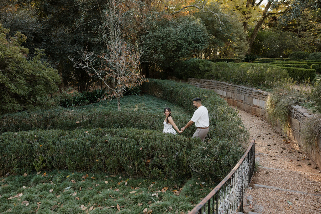 Couple walking through manicured gardens at Hills & Dales Estate during golden hour in LaGrange, GA
